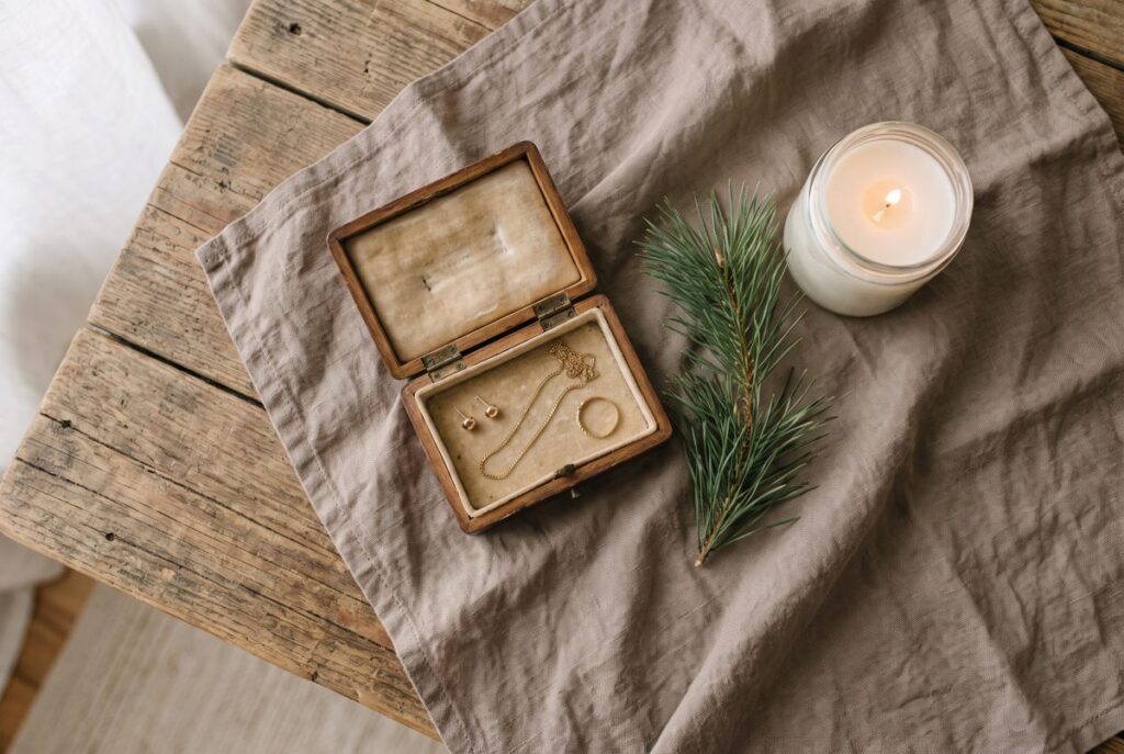 Petit coffret en bois ouvert avec des puces d'oreilles, une chaîne fine et une bague dorées